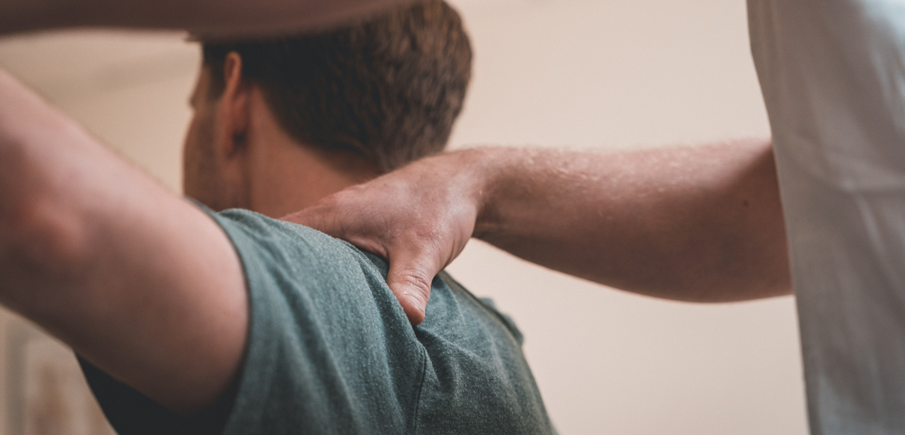 Patient en train de se faire manipuler l'épaule par un professionnel de santé