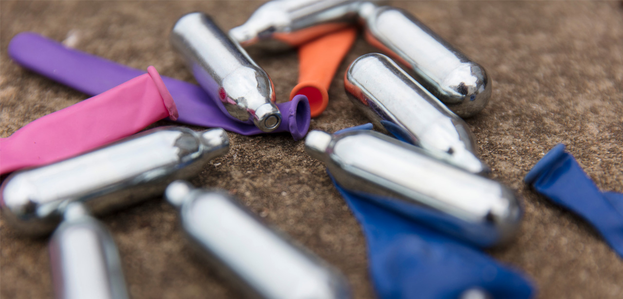 Cartouches métalliques de protoxyde d’azote (gaz hilarant) usagées et ballons de baudruche colorés abandonnés sur le sol