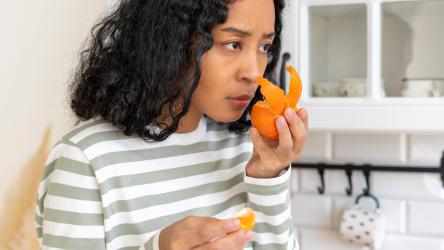 Photo d'une femme illustrant les effets à long terme après avoir eu le coronavirus (perte d'odorat en sentant un fruit)