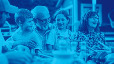 Portrait d'un grand-père aîné tenant ses petits-enfants sur les genoux lors d'un dîner en plein air.