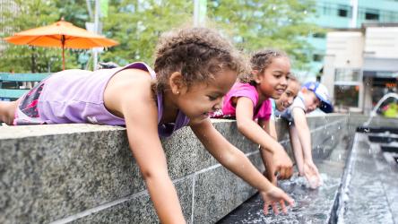 Visuel enfants se rafraîchissant dans une fontaine en ville